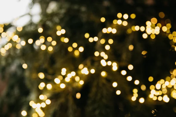 Hafif bokeh odaklanmış arkaplan. Noel ağacı ışıklarının bulanık fotoğrafı. Altın ışık efektleri. tatiller, arka plan ve aydınlatma kavramı