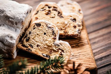 Ahşap arka planda Noel çalıntısı. Geleneksel yılbaşı Alman tatlıları parçalara ayrılmış. Fındıklı kek, badem ezmeli kuru üzüm ve kesme tahtasında kurutulmuş meyve. Xmas için pişirme