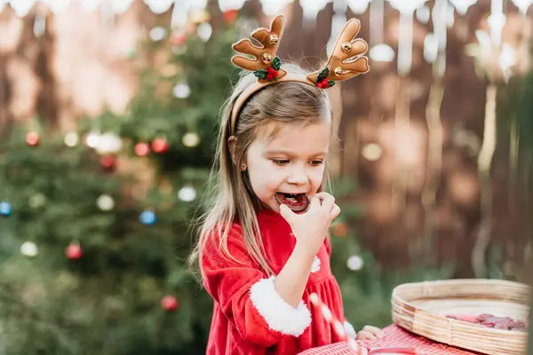 Christmas in july. Child waiting for Christmas in wood in july. portrait of little girl drinking hot cocoa with marshmallow and gingerBread man cookies. Merry Christmas and Happy Holidays.