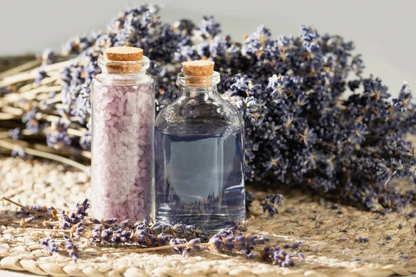lavender oil and salt in glass bottle on background of dry lavender flowers. bottle of essential Herbal oil or infused water. aromatherapy spa massage concept. Natural cosmetics for the body.