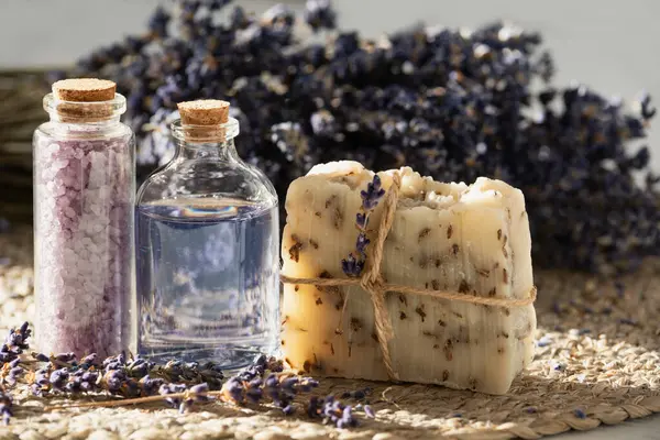 lavender oil and salt in glass bottle on background of dry lavender flowers. bottle of essential Herbal oil or infused water. aromatherapy spa massage concept. Natural cosmetics for the body.