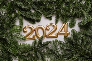 Tatil geçmişi. Mutlu yıllar 2024. 2024 yılının numaraları, arka planda köknar ağacıyla altın mumlarla yapıldı. Yeni yılı kutluyoruz, yakın plan. Metin için boşluk