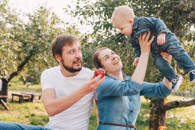 Mutlu aile portresi sarılıyor ve dışarıda birlikte vakit geçiriyorlar. Bahçede küçük bir bebeği olan genç bir anne ve baba. Elma hasadı ve sonbaharda çiftlikte toplama.