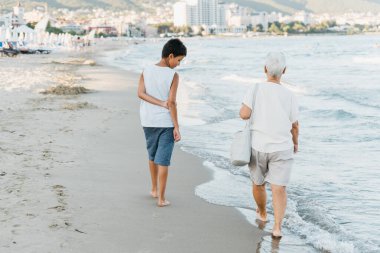 Denizde yaz tatili. Oğlan ve kıdemli kadın deniz kenarında. Torunuyla birlikte büyük anne denizde dinleniyor, sahilde koşuyor yaz tatilinde eğleniyor. Aktif ebeveynler, çocuklu insanlar..