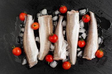 Çiğ balık yahnisi. Beş çiğ balık fileto, buzlu organik taze domates, arka planda yiyecek. en üstteki görünüm.