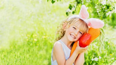 çocukluk, Paskalya kutlamaları, mevsimsel mutluluk, Paskalya yumurtası avı. Bahçede yumurta toplamak için koşan tavşan kulaklı bir kız çocuğu. Paskalya geleneği. Renkli yumurtalarla dolu sepeti olan bebek.
