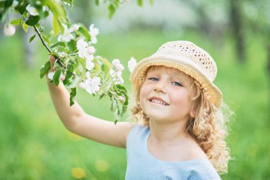 girl sniffing flowers of apple orchard. garden with flowering trees. Allergy season. Soft focus. Girl enjoying floral aroma. Child enjoy life without allergy.