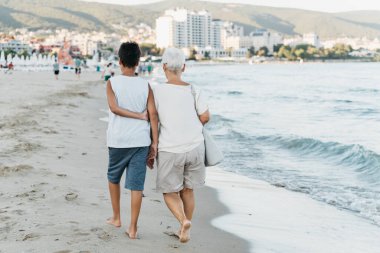 Denizde yaz tatili. Oğlan ve kıdemli kadın deniz kenarında. Torunuyla birlikte büyük anne denizde dinleniyor, sahilde koşuyor yaz tatilinde eğleniyor. Aktif ebeveynler, çocuklu insanlar..