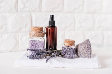 Lavanta ve Cam Kavanozlar 'ın oynadığı Spa ve Sağlık Sahnesi. Aromaterapi seansı. Cam bir vazoda kurumuş lavanta çiçekleri, mantar kapaklı şişeler, gerekli yağ, kese ve kehribar sprey şişesi.