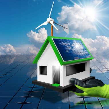 Koruyucu iş eldivenli bir el, güneş panelleri ve çatıda küçük bir rüzgar türbini olan küçük bir model ev tutuyor. Yenilenebilir enerji kavramı. Arka planda bulutlar ve güneş ışınları olan mavi gökyüzü.
