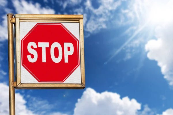 Close-up of a stop road sign against a clear blue sky with clouds and sunbeams, photography