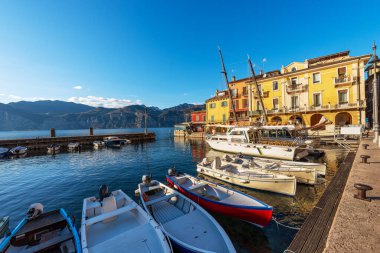 Malcesine köyü. Limanda küçük tekneler ve feribotlar demirli ve renkli evler var. Garda Gölü kıyısındaki ünlü turizm beldesi (Lago di Garda). Verona ili, Veneto, İtalya, Güney Avrupa.