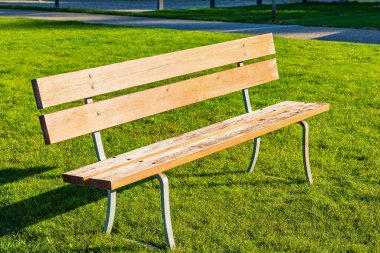 Yeşil çimenlikteki boş bir ahşap bankın yakın çekimi. Malcesine köyü, Garda Gölü kıyısındaki turizm beldesi (Lago di Garda), Veneto, İtalya, Avrupa.