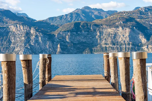 ガルダ湖 Lago Garda とイタリアアルプスの海岸にある木製の桟橋は マルセシーン ヴェローナ県 イタリア ヴェネト州 南ヨーロッパの小さな村からの眺めです ロンバルディア州の海岸を背景に — ストック写真