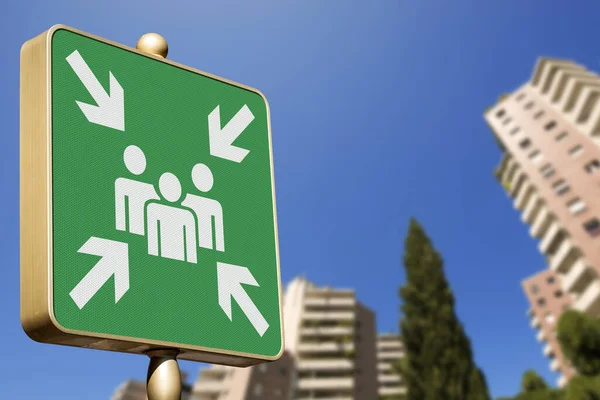 Emergency assembly point. Closeup of a green sign in a city against a clear blue sky. Outdoor sign indicating where people should congregate following an emergency evacuation of the building