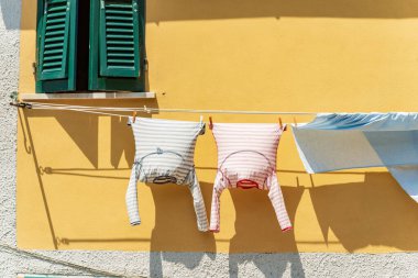 Çamaşırlar pencerenin dışında asılı, çamaşır ipinde güneşte kurusun diye. Tellaro köyü, Liguria, İtalya, güney Avrupa. İki pijama ve bir çarşaf..