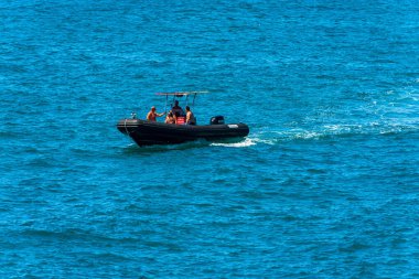 LA SPEZIA, ITALY - 27 Temmuz 2022: Akdeniz 'de güneşli bir yaz günü, La Spezia Körfezi, Liguria, İtalya, Avrupa' da hareket halindeki bir grup yetişkinle motorize siyah sandal.