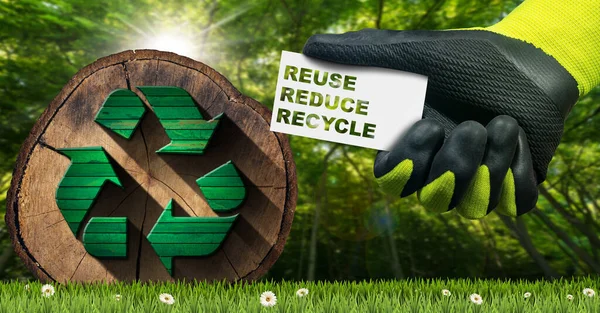 Manual worker with work gloves holding a business card with text Reuse, Reduce and Recycle. Green meadow with a cross section of a tree trunk with a recycle symbol and a green forest on background.