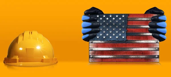 幸せな労働者の日のコンセプト アメリカ合衆国の金属国旗を保持する作業手袋を持つ手動労働者 米国旗 ハードハットとスペースをコピーオレンジの背景に ストック写真