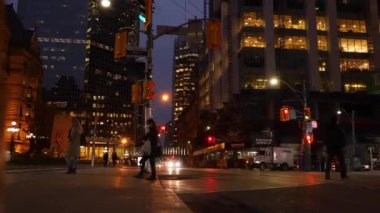 Zaman aşımı - Toronto şehir merkezinde akşam, insanlar ve arabalar kavşakta farklı yönlere hareket ediyorlar, binalar ışıklarını yaktı.