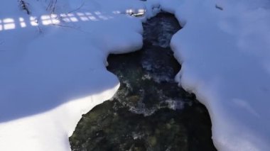 Harika bir kış masalı. Karlı bir orman, bir dağ nehri, dağların üzerinde güneş. Doğal manzara.