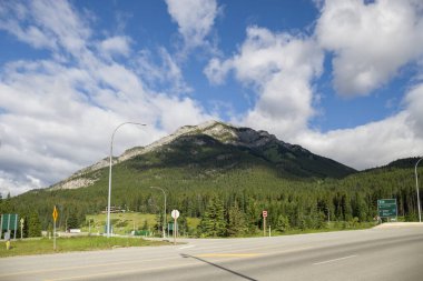 Highway in mountains. Trans Canada Highway with a perfect asphalt at sunrise in summer.  Banff National Park, Alberta, Canada. Travel background. Tourism hiking - a road in the forest between the mountains. Great view, summer vacation, 