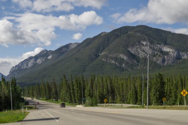 Highway in mountains. Trans Canada Highway with a perfect asphalt at sunrise in summer.  Banff National Park, Alberta, Canada. Travel background. Tourism hiking - a road in the forest between the mountains. Great view, summer vacation, 