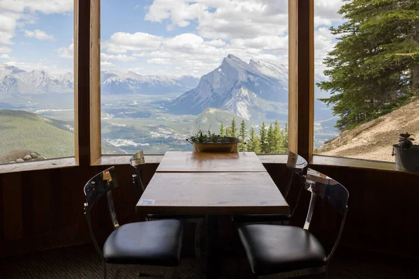 Inside cafe with a great view of the mountains outside. An empty table and chairs without people, wide panoramic windows with a beautiful view. Tourism in the mountains in summer.