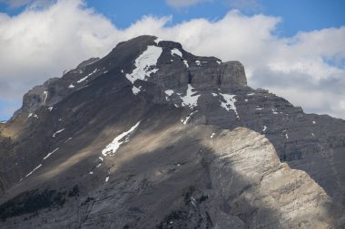 Mountain peaks of the Rocky Mountains in summer. Natural landscape background. Coniferous forest, remnants of snow. blue sky and clouds. Tourist season in Banff, Canada