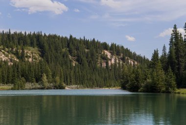 Kanada manzarası - Banff Ulusal Parkı, Alberta - Dağlara yaz yolculuğu, güzel mavi göl ve kozalaklı orman.