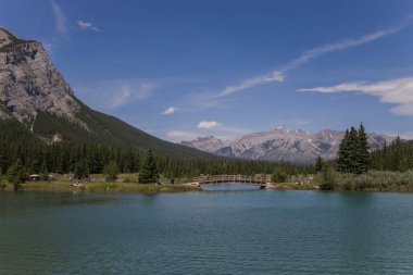  Tahta köprüsü olan çağlayan göletler. Uzakta Rundle Dağı 'nın olduğu piknik alanı Banff Ulusal Parkı, Alberta, Kanada