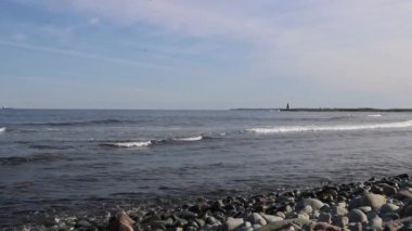 Arka planda mavi gökyüzü olan deniz manzarası. Hafif okyanus dalgaları, seçici odaklanma, ön planda bulanık taşlar - Atlantik kıyısı - Halifax, Kanada. Arka planda deniz feneri