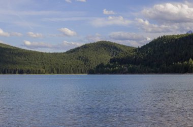 Yaz tatili dağlarda - Minnewanka Gölü gezisi. Kayalık dağlar, berrak mavi su, kamp alanı ve yeşil orman. Banff, Alberta, Kanada