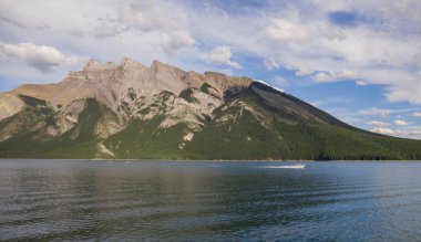 Yaz tatili dağlarda - Minnewanka Gölü gezisi. Kayalık dağlar, berrak mavi su, kamp alanı ve yeşil orman. Banff, Alberta, Kanada