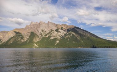 Yaz tatili dağlarda - Minnewanka Gölü gezisi. Kayalık dağlar, berrak mavi su, kamp alanı ve yeşil orman. Banff, Alberta, Kanada