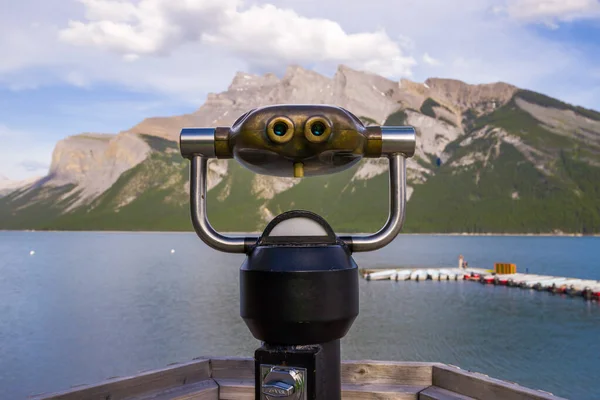 stock image Coin operated binoculars on Lake Minnewanka. Rocky mountains, clear blue water and green forest. Summer vacation in the mountains - a trip to Banff, Alberta, Canada