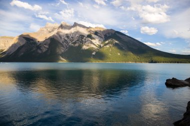 Dağ Gölü manzarası manzarası insanları - orman, manzaralı mavi göl ve ufukta Rocky Dağları. Minnewanka Gölü, Banff il parkı, Alberta, Kanada