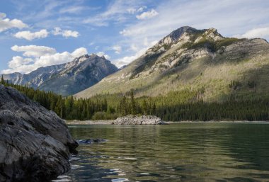 Güzel dağ manzarası - kristal berrak su ile dağ gölü, yeşil kozalaklı orman, kayalık dağlar ve mavi bulut gökyüzü - Banff taşra parkı, Alberta, Kanada