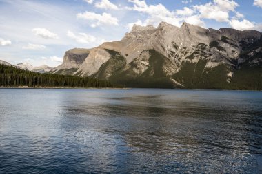 Dağ Gölü manzarası manzarası insanları - orman, manzaralı mavi göl ve ufukta Rocky Dağları. Minnewanka Gölü, Banff il parkı, Alberta, Kanada