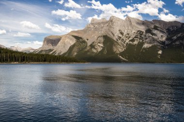 Dağ Gölü manzarası manzarası insanları - orman, manzaralı mavi göl ve ufukta Rocky Dağları. Minnewanka Gölü, Banff il parkı, Alberta, Kanada