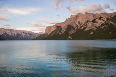 Dağ Gölü manzarası manzarası insanları - orman, manzaralı mavi göl ve ufukta Rocky Dağları. Minnewanka Gölü, Banff il parkı, Alberta, Kanada