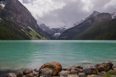 Banff Ulusal Parkı, Alberta, Kanada 'daki Muhteşem Louise Gölü. Yağmurdan sonraki gün bulutlu. Mavi göl suyu ve sisli tepeler. Seyahat için ünlü bir yer. Idyllic yaz manzarası. 
