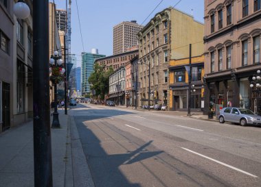 Şehir merkezinin Vancouver manzarası. Caddenin genel planı - eski ve modern binalar, yollar, ticari işletmeler güneşli yaz günlerinde. 