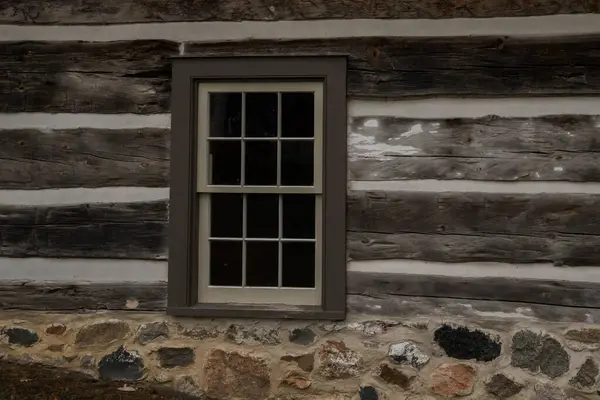 Rustic window in a wooden country cottage. Grunge brown wood wall. A close-up view of the log cabin. Great texture and architectural details and features.