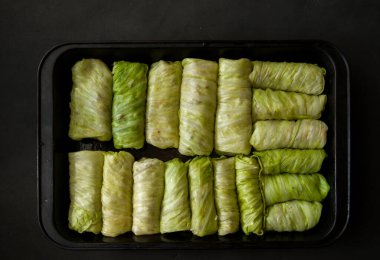 Siyah arka planda fırın tepsisine doldurulmuş lahana ruloları. Seçici odaklanma. Ton halinde. Ukrayna geleneksel yemeği. Doğu Avrupa mutfağı. Üst görünüm, kopyalama alanı ile.