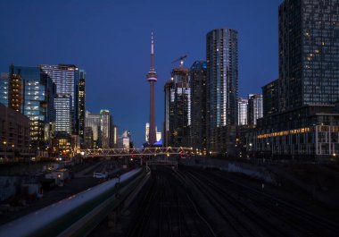 Finans bölgesinde şehir merkezinde günbatımı. Demiryolu kavşağı, apartmanlar, ofis binaları aydınlatıldı. Skyline Toronto, Ontario, Kanada