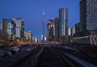 Finans bölgesinde şehir merkezinde günbatımı. Demiryolu kavşağı, apartmanlar, ofis binaları aydınlatıldı. Skyline Toronto, Ontario, Kanada
