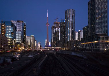 Finans bölgesinde şehir merkezinde günbatımı. Demiryolu kavşağı, apartmanlar, ofis binaları aydınlatıldı. Skyline Toronto, Ontario, Kanada - 02.06.2024