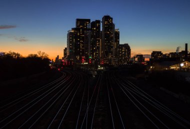 Gece şehir merkezinde. Finans bölgesinde günbatımı. Demiryolu kavşağı, apartmanlar, ofis binaları aydınlatıldı. Skyline Toronto, Ontario, Kanada