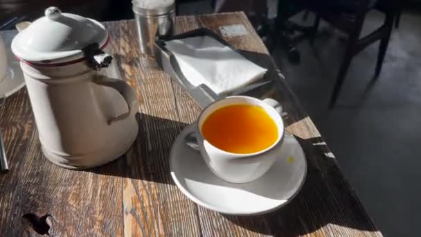 湯気のある熱いシーバソーン茶の日光浴は ティーポットやナプキンの近くの古い木製のテーブルの上にあります 季節のインフルエンザや風邪の代替医療としての天然のホットドリンクの概念 トップ表示 — ストック動画